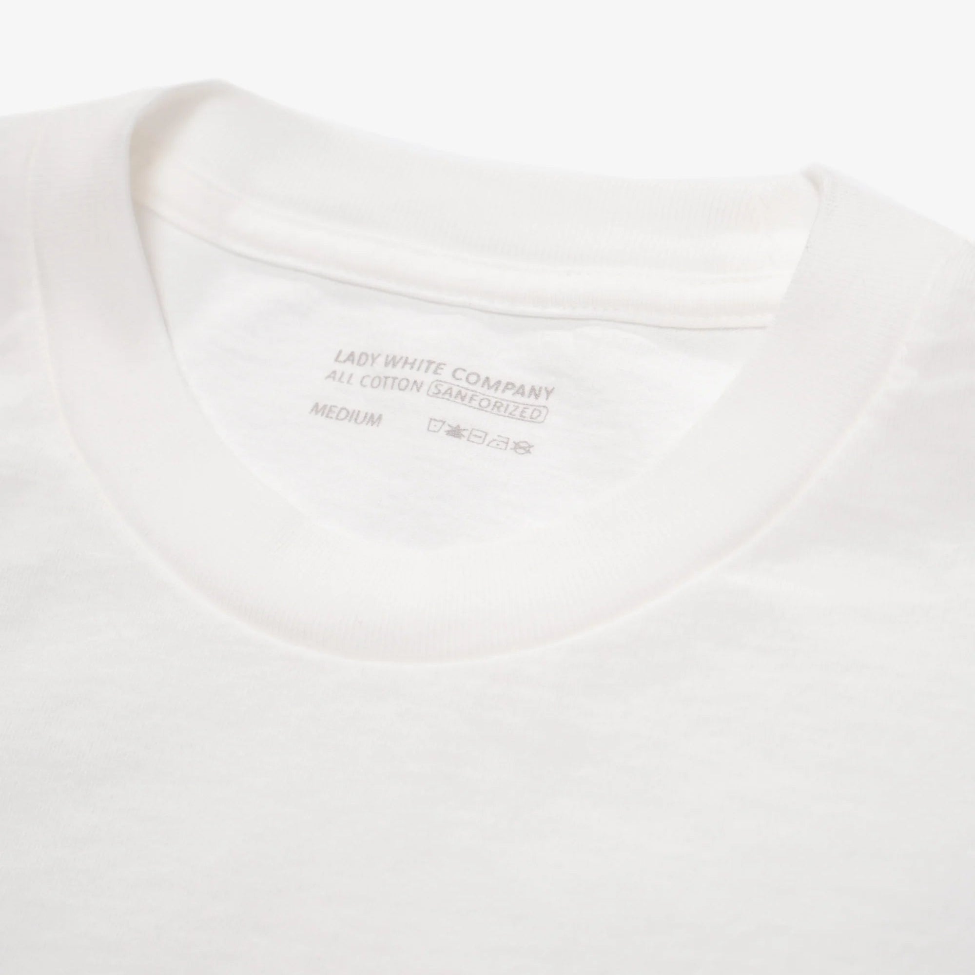 Close-up of a white t-shirt with a brand label on a white background