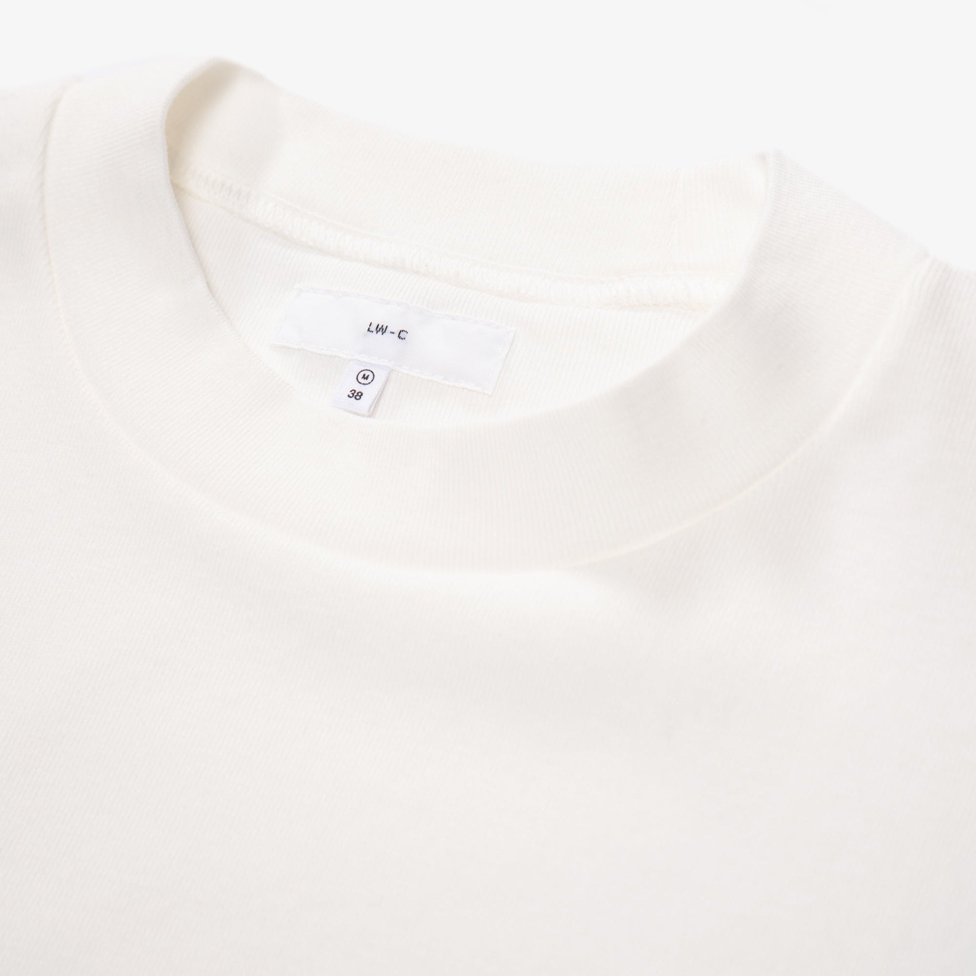 Close-up of a white t-shirt with a brand label on a white background