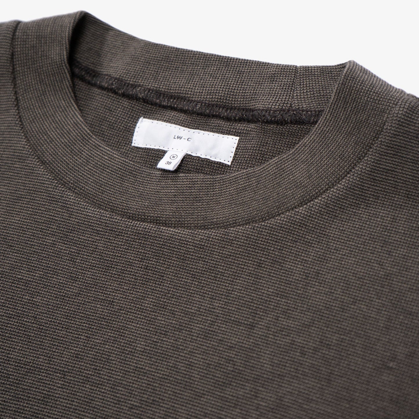 Close-up of a dark t-shirt with a brand label on a white background